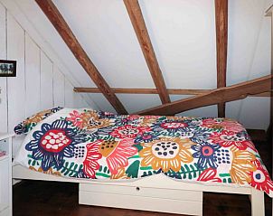 Kleurrijke slaapkamer in Vakantiehuis in Benneveld, Drenthe, met houten balken en bloemendekbed.