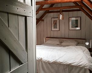 Landelijke slaapkamer in Vakantiehuis in Benneveld, Drenthe, met houten deur en sfeervolle verlichting.