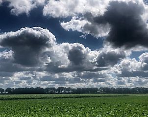 Uitgestrekte wolkenluchten boven de velden rond Vakantiehuis in Benneveld, Drenthe, bieden serene uitzichten.
