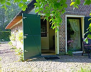 Open deur naar het Huisje in Benneveld, vakantiehuis in Drenthe, omgeven door groen en rust.