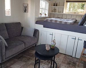Gezellige binnenruimte met zithoek en bed in Vakantiehuis in Erica, Zuidoost Drenthe, voor een comfortabel verblijf.