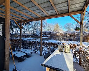 Sneeuw bedekt terras met ligstoelen in Vakantiehuis in Erica, Drenthe, voor een winterse ontsnapping.