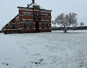 Sneeuwlandschap rondom Vakantiehuisje in 2e Exloermond, Drenthe, met charmante gevel en winterse sfeer.