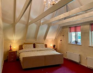 Sfeervolle slaapkamer in vakantiehuisje Klijndijk, Drenthe, met groot bed en houten balken.