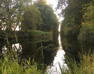 Rustige waterkant bij vakantiehuis Klijndijk, Zuidoost Drenthe, omgeven door weelderige bomen.