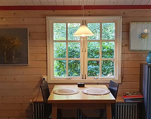 Eettafel bij raam in Vakantiehuisje in 't Haantje, Drenthe, met uitzicht op groene tuin.