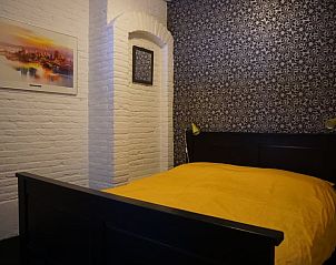 Sfeervolle slaapkamer met geel dekbed in Vakantiehuis in Odoornerveen, Zuidoost Drenthe.