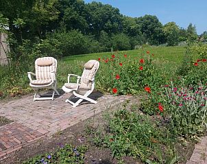 Rustige tuin met zitje bij Vakantiehuis in Zwinderen, omgeven door bloemen in Drenthe.