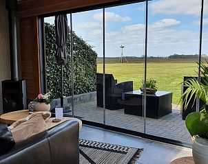 Lichte woonkamer met glazen schuifdeuren in Huisje in Fluitenberg, vakantiehuis in Zuidwest Drenthe.