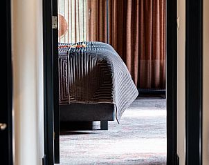 Doorkijk naar slaapkamer in Vakantiehuis in Fluitenberg, Zuidwest Drenthe, met warme tinten.