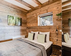 Slaapkamer met houten muren in Huisje in Fluitenberg, rustieke charme in Zuidwest Drenthe.