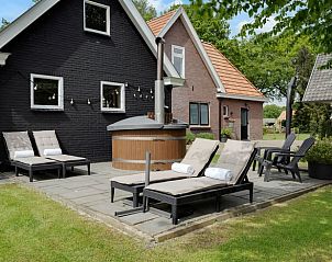 Wellnesshoek met ligbedden en hottub bij Huisje in Fluitenberg, Zuidwest Drenthe.