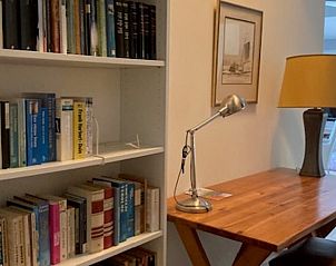 Gemtliche Leseecke im Ferienhaus in Diever, Sdwest-Drenthe, mit Bcherregal und Holzschreibtisch fr einen entspannten Aufenthalt.