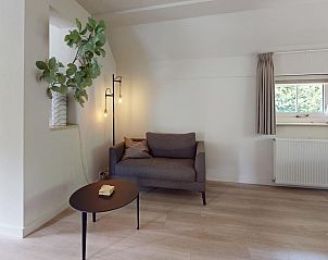 Gemtliches Wohnzimmer des Ferienhauses Borre Bos in Diever, Sdwest-Drenthe, mit bequemem Sofa und stimmungsvoller Beleuchtung.