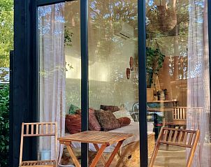 Gezellige zithoek met glazen gevel in Huisje in Zuidwolde, vakantiehuis in Zuidwest Drenthe, omgeven door rustgevende natuur.