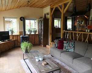 Gemtliches Wohnzimmer des Ferienhauses in Zuidwolde, Drenthe, mit rustikaler Einrichtung und Blick auf die grne Umgebung.