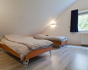 Gezellige slaapkamer in Vakantiehuisje in Ruinen, Drenthe, met twee comfortabele bedden en uitzicht op de groene omgeving.