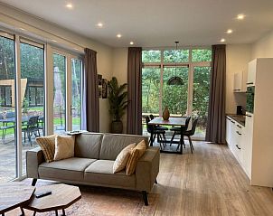 Ruime woonkamer van Vakantiehuis Just Nature in Ruinen, Drenthe, met uitzicht op het groene terras.