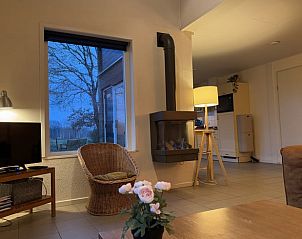 Gemtliches Wohnzimmer im Ferienhaus in Ruinen, Sdwest-Drenthe, mit Blick auf die Natur und einem gemtlichen Kamin.