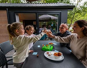 Gezin geniet van een drankje op het terras van Vakantiehuis Forest Lodge 4, Ruinen, Drenthe.