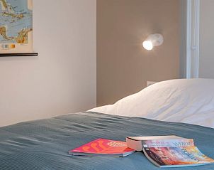 Slaapkamer in Vakantiehuisje in Dwingeloo, Zuidwest Drenthe, met comfortabel bed en leesmateriaal.