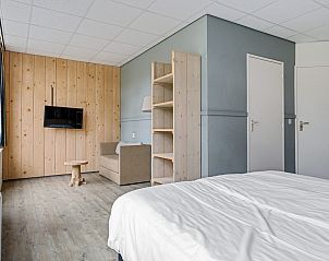 Sfeervolle slaapkamer in Groepsaccommodatie de Komeet, Dwingeloo, Drenthe, met moderne inrichting en houten details voor een rustiek verblijf.
