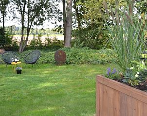 Groene tuin bij Vakantiehuis in Dwingeloo, Drenthe met uitnodigende zitjes.