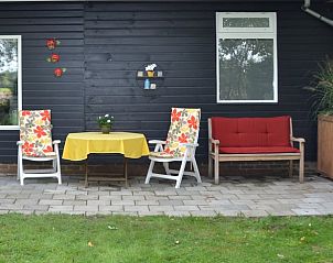 Gezellig terras bij Vakantiehuis in Dwingeloo, Drenthe met kleurrijke stoelen.
