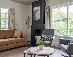 Gezellige woonkamer van Bungalow Saturnus in Dwingeloo, Drenthe, met comfortabele zitruimte en uitzicht op de groene natuur.