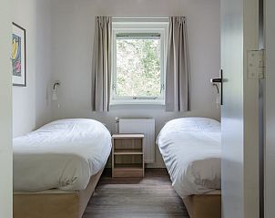 Gezellige slaapkamer in Bungalow Saturnus, Dwingeloo, met twee eenpersoonsbedden en uitzicht op de groene omgeving van Zuidwest Drenthe.