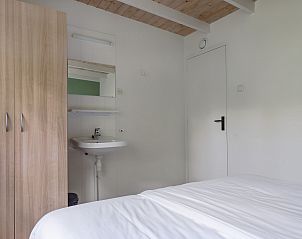 Slaapkamer in Bungalow Saturnus, een vakantiehuis in Dwingeloo, Zuidwest Drenthe, met een comfortabel bed en een praktische wastafel.