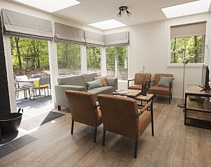 Gezellige woonkamer van Bungalow Mercurius in Dwingeloo, Zuidwest Drenthe, met uitzicht op het bosrijke terras.