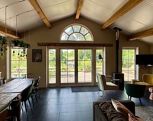 Gezellige binnenruimte van Huisje in Dwingeloo, vakantiehuis in Zuidwest Drenthe met uitzicht op groene natuur door grote ramen.