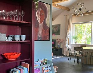 Gezellige binnenruimte van Huisje in Dwingeloo, Zuidwest Drenthe, met kleurrijke kunst en ruime eethoek voor een ontspannen vakantie.