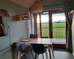 Gemtlicher Innenbereich des Ferienhauses in Ruinerwold, Sdwest-Drenthe mit Blick auf grne Felder vom Esszimmer aus.