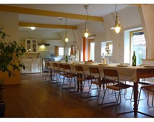 Gezellige eetruimte in Vakantiehuisje in Wapse, Drenthe, met lange houten tafel en moderne keuken.