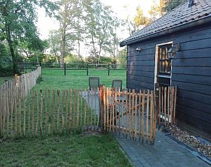 Ruime tuin bij Vakantiehuis in Wapse, Zuidwest Drenthe, met houten hek en zitplaatsen.