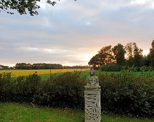 Rustieke tuin van Vakantiehuisje in Wapse, Zuidwest Drenthe, met uitzicht op groene velden en een serene zonsondergang.