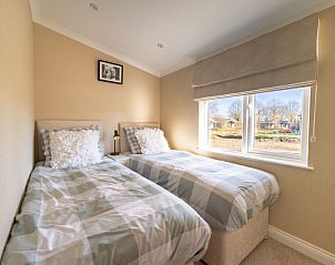 Sfeervolle tweepersoonsslaapkamer in Vakantiehuis Hackfort 6, Biddinghuizen, met uitzicht op de groene omgeving.