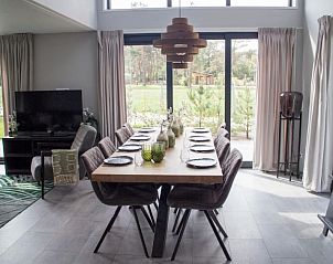 Eetkamer in Vakantiehuis Bosvilla Sauna 8 in Biddinghuizen met grote tafel en tuinzicht.