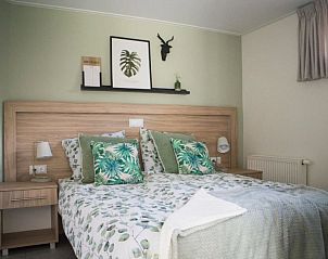 Slaapkamer in Vakantiehuis Bosvilla Sauna 8 in Biddinghuizen met groen decor en comfortabel bed.