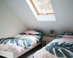 Zolderkamer in Vakantiehuis Bosvilla Sauna 8 in Biddinghuizen met twee bedden en dakraam.