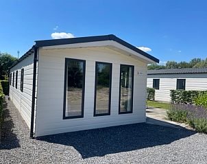 Chalet in Biddinghuizen onder een heldere blauwe lucht, biedt een zonnig verblijf in Oostelijk Flevoland.