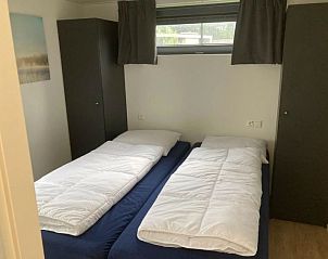 Comfortabele slaapkamer in Vakantiehuis Cube Elite 6, Biddinghuizen, Flevoland met twee eenpersoonsbedden en opbergruimte.