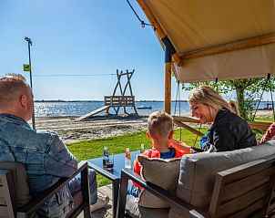 Gezellig samenzijn op het terras van Vakantiehuis Cube Elite 6, Biddinghuizen, Flevoland met uitzicht op het meer.