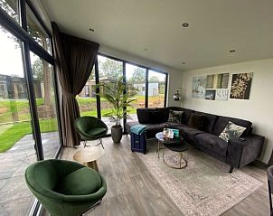 Gezellige woonkamer van Vakantiehuis Cube Split 6 in Biddinghuizen met uitzicht op de groene omgeving.