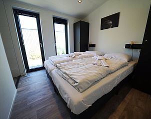 Hoofdslaapkamer in Vakantiehuis Cube Split 6, biedt een serene ambiance voor een goede nachtrust in Biddinghuizen.