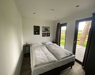 Hoofdslaapkamer met terras in Vakantiehuis Cube Split 6, biedt luxe en comfort in Biddinghuizen, Flevoland.