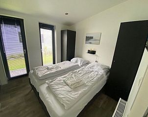 Slaapkamer met uitzicht op de tuin in Vakantiehuis Cube Split 6, ideaal voor een serene vakantie in Biddinghuizen.