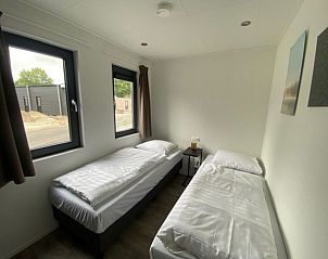 Lichte slaapkamer met twee bedden in Vakantiehuis Cube Split 6, biedt rust en comfort in Biddinghuizen.